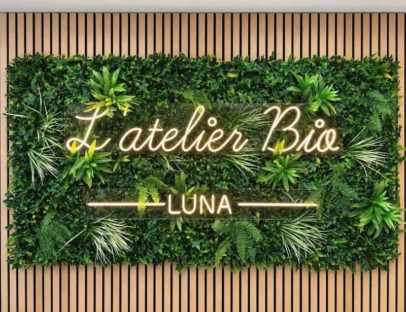 Mur végétal et néon « L'atelier Bio Luna » dans le salon de coiffure d'Ennery